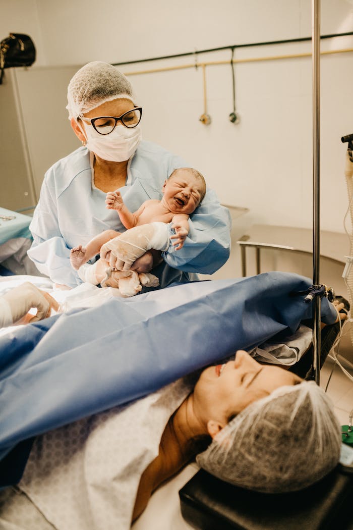 A doctor holds a newborn baby in a hospital setting post-delivery.