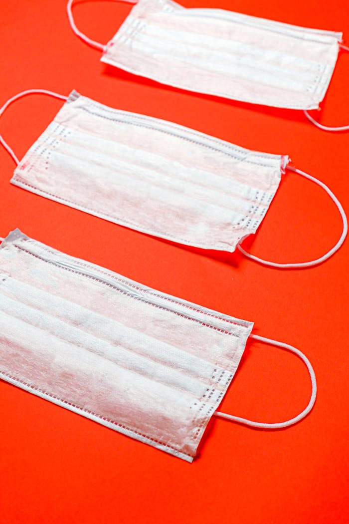 Disposable face masks arranged on a bright red surface symbolizing health and protection.