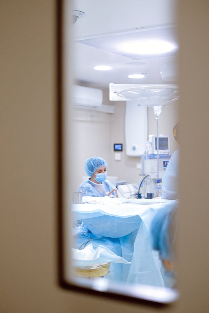 View of a surgeon working in an operating room through a door window, emphasizing medical precision.